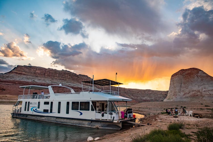 Houseboat on Lake Powell as the sun sets behind the cliffs