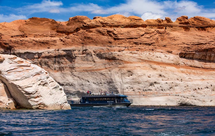 Tour boat traversing Lake Powell with dramatic cliffs in the background
